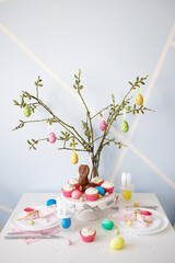 easter concept - decorated table with pussy willow branch, cupcakes, painted eggs and bunnies