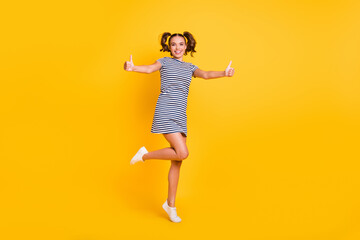 Photo of cute adorable young lady dressed striped outfit jumping showing thumbs up isolated yellow color background