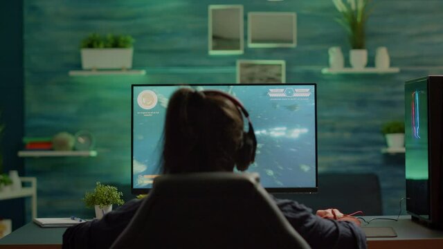 Upset professional woman gamer wearing headset losing space shooter game in cybersport competition. Tired pro cyber player gaming online video games on powerful personal computer with RGB lights.