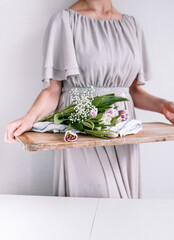 Woman holding flowers in a brown cutting board, for Nordic feeling and vibes. 