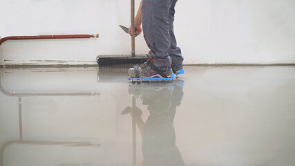 A hired painter paints the floor in the apartment. The interior of an apartment under construction....
