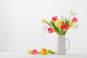 beautiful   tulips in white jug on white background