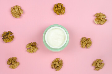 open jar of cream and walnuts on a pink background. Organic cosmetics for skin care. Mock-up bottle for branding and label