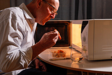 Stockholm, Sweden A man eats alone in front of the microwave.