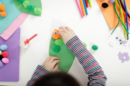 young girl hand makes caterpillar craft for home schooling