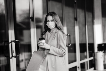 Young female wearing a mask for prevent virus with shopping bags on narrow street in Europe.