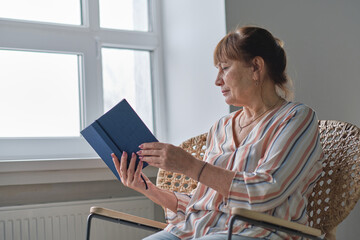 Senior woman at home reading book. smiling older person enjoying reading books. retirment home care