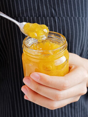 Red and yellow jam on plank wood and slice bread.