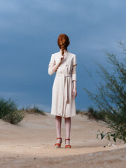 Full-length red-haired woman with a pigtail on her face in a sundress and red shoes