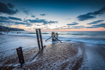 Sunrise at The Warren, Folkestone. A winter sunrise lights the sky behind the old sea groynes on...