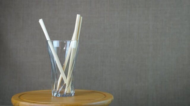 Bamboo straw in the glass. A view of a woman hands putting bamboo straws in the glass. A concept of no use plastic at home.
