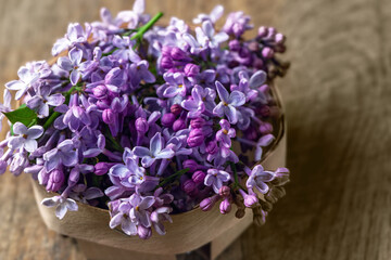 Lilac flowers in basket on wooden background