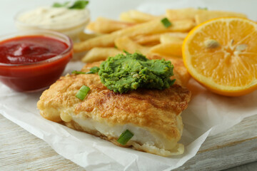Tasty fried fish and chips on white board, close up