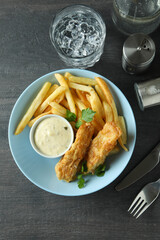 Concept of tasty eating with fried fish and chips on dark textured table