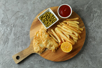 Concept of tasty eating with fried fish and chips on gray textured background