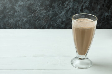 Glass of chocolate milkshake on white wooden table