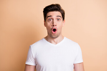 Photo of crazy amazed young man open mouth unbelievable information isolated on pastel beige color background