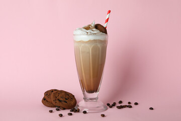 Glass of milkshake, coffee seeds and cookies on pink background