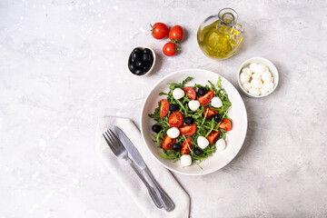 Typical dishes of the Mediterranean diet : mozzarella balls, black olives, olive oil, salad with tomatoes and arugula, bruschetta. Healthy Food Italian cuisine. 