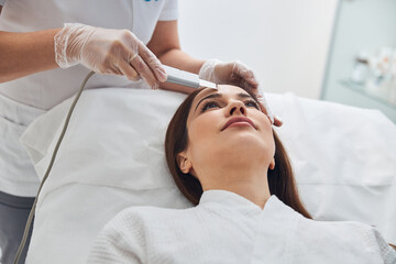 Obraz na płótnie Canvas Beautiful woman receiving facial treatment in cosmetology clinic