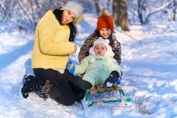 family posing in the winter forest, mother and children, bright sunlight and shadows on the snow, beautiful nature