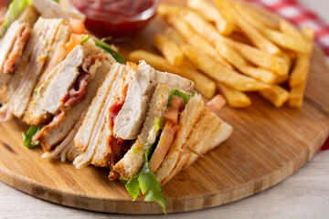 Club sandwich and French fries with ketchup sauce on wooden table