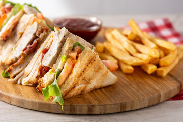 Club sandwich and French fries with ketchup sauce on wooden table