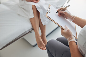 Doctor writing on clipboard during meeting with patient