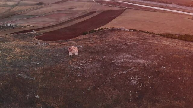 Tractor labrando la tierra para sembrar cereales, trigo, casa abandonada sobre el cerro