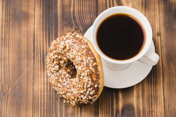 White cup of black coffee and donut with nuts.