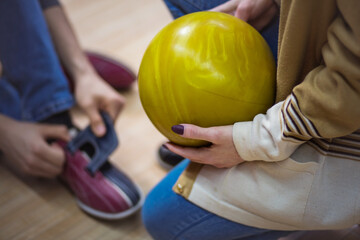 Young couple in a bowling alley. Man is wearing bowling shoes. Woman holding a ball.