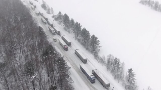 Trucks are stuck in traffic on a snow-covered highway. Thousands stranded on highway as major snowstorm and blizzard hits hard causing
