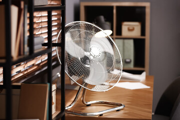 Modern electric fan on table in office