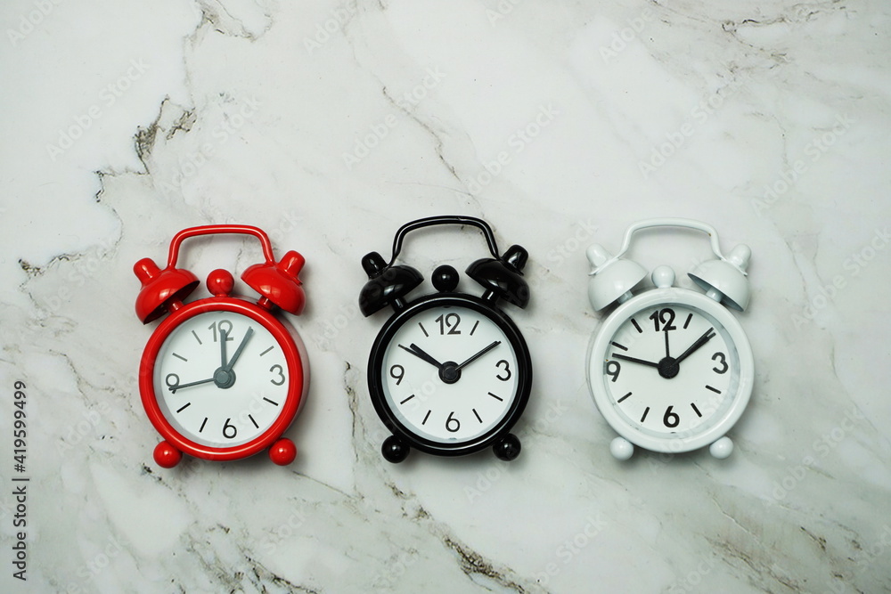 Poster top view of alarm clocks with different time flat lay composition on marble background