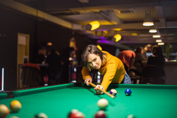 Woman playing billiard alone. She is focused on game.