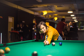 Woman playing billiard alone.