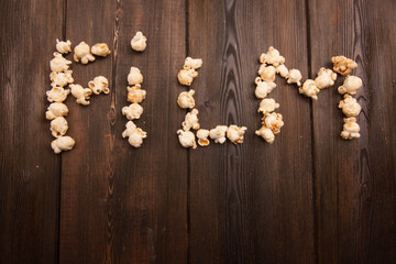 Fototapeta na wymiar popcorn laid out word movie on wooden background snack