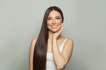 Happy pretty model woman with clear skin and long healthy straight hair smiling on white background. Skincare and facial treatment concept