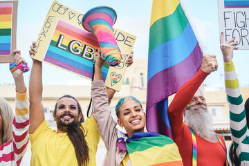 Gay people having fun at pride parade with LGBT flags and banners outdoors - Main focus on senior...