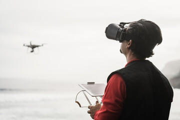 Engineer drone pilot flying with quadcopter outdoor on the beach - Focus on face
