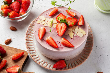 Close-up of raw vegan cake with almond and oatmeal flour, raisins and coconut butter base, cashew and strawberry mousse, gluten, egg and sugar free. Healthy food concept .
