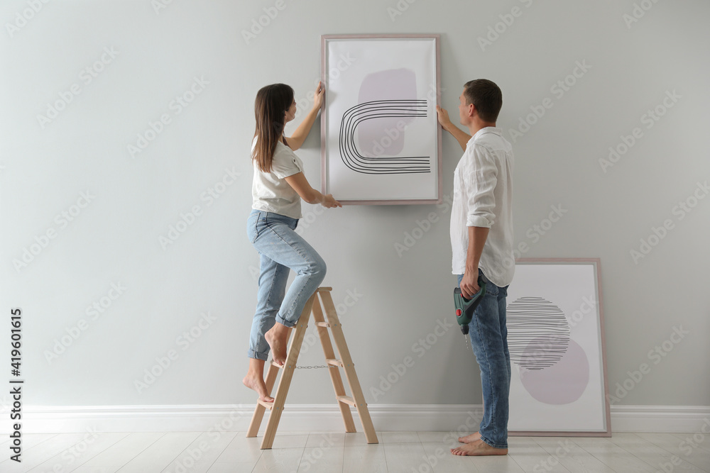 Sticker couple hanging picture on wall together in room. interior design