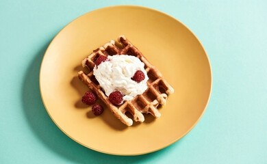 Sweet traditional dessert. Top view of a traditional Belgian waffle with cream cheese or ice cream and fresh raspberries