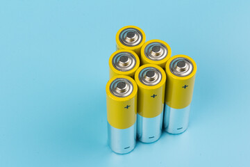 Photo of gray-yellow alkaline AA batteries on blue background. Recycling of rechargeable NiMH...