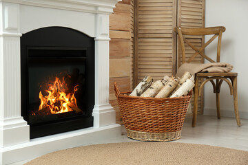 Firewood in wicker basket near fireplace indoors