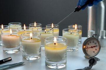 aroma scented candle glasses are on the white table with fragrance oil during the burning test process in the lab checking for the soot and temperature burning time before selling in the candle market