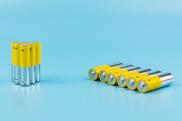 Photo of gray-yellow alkaline AA batteries on blue background. Recycling of rechargeable NiMH...