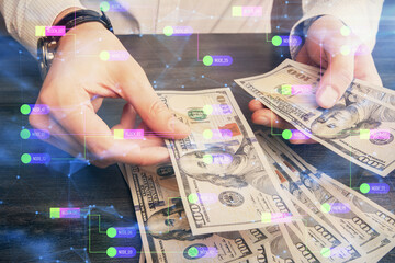 Double exposure of technology drawing hologram and us dollars bills and man hands. Data concept