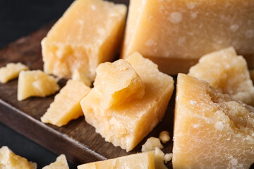 Pieces of delicious parmesan cheese on wooden board, closeup