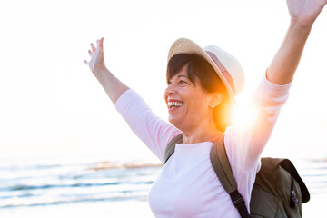 Happy senior woman with arms up having fun on the beach - Mental health and optimism concept